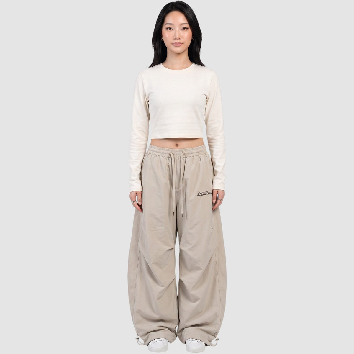 Y2K STUDIO beige oversized nylon joggers with a wide elastic waist and white embroidered logo on the right thigh.