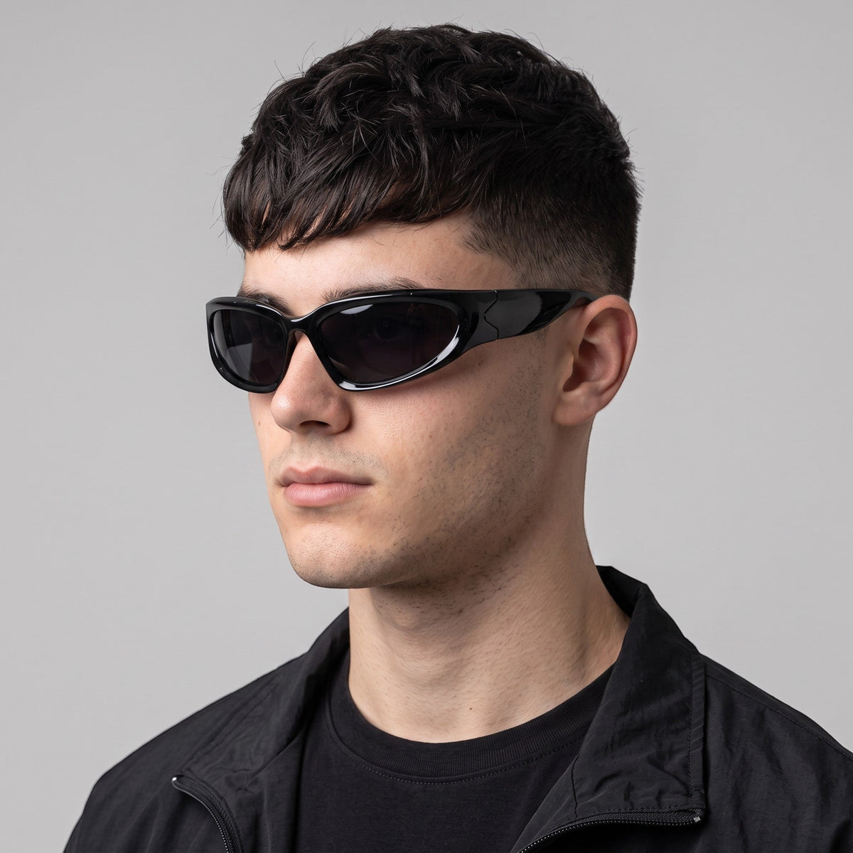 Y2K STUDIO black wraparound gorpcore sunglasses with dark tinted lenses worn by a man in a techwear style
