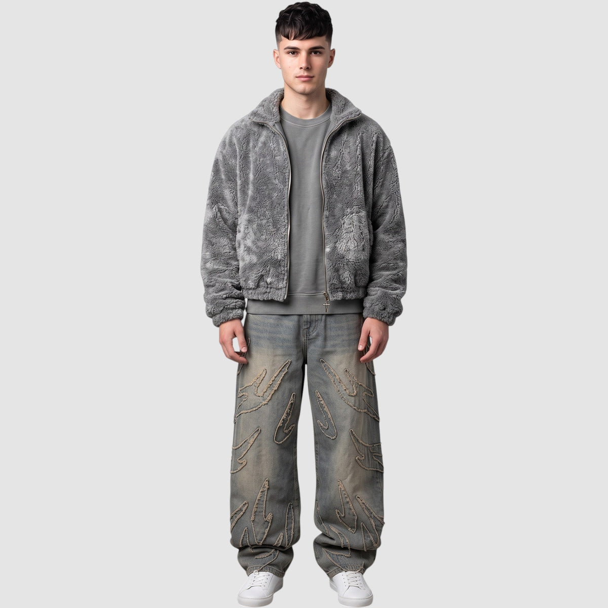 Y2K STUDIO baggy grey denim jeans featuring raw-edge flame appliqués, worn by a model with a grey fleece jacket.