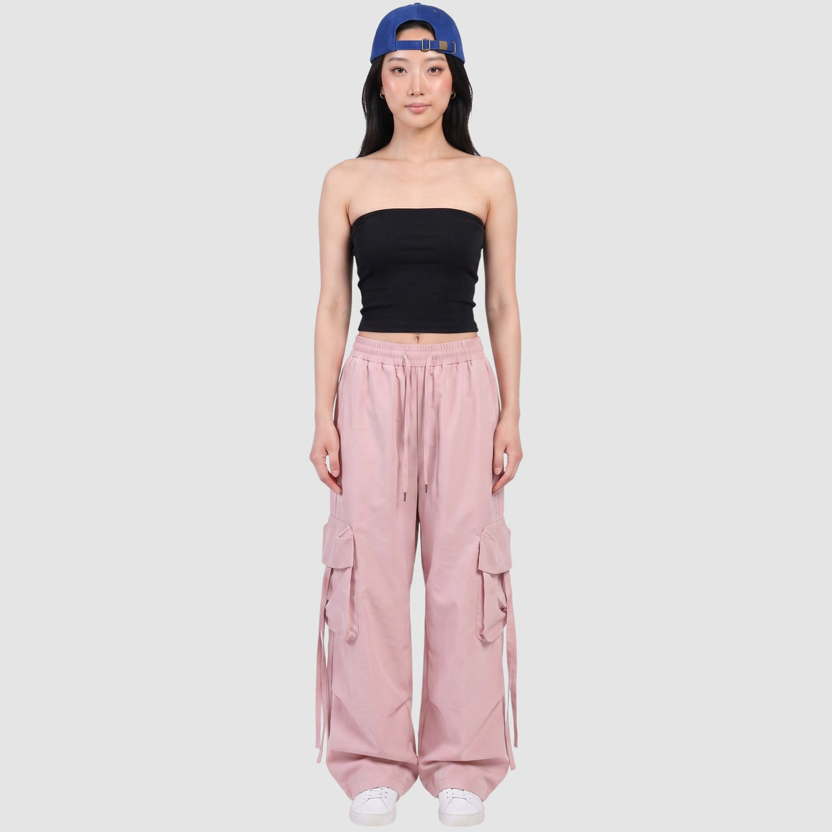 Model wearing Y2K STUDIO powder pink parachute cargo pants with side pockets, drawstring waist, and loose wide fit.