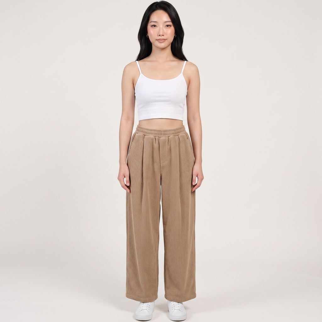 Model wearing Y2K Studio beige wide-leg corduroy trousers with an elasticated waist, paired with a white cropped top