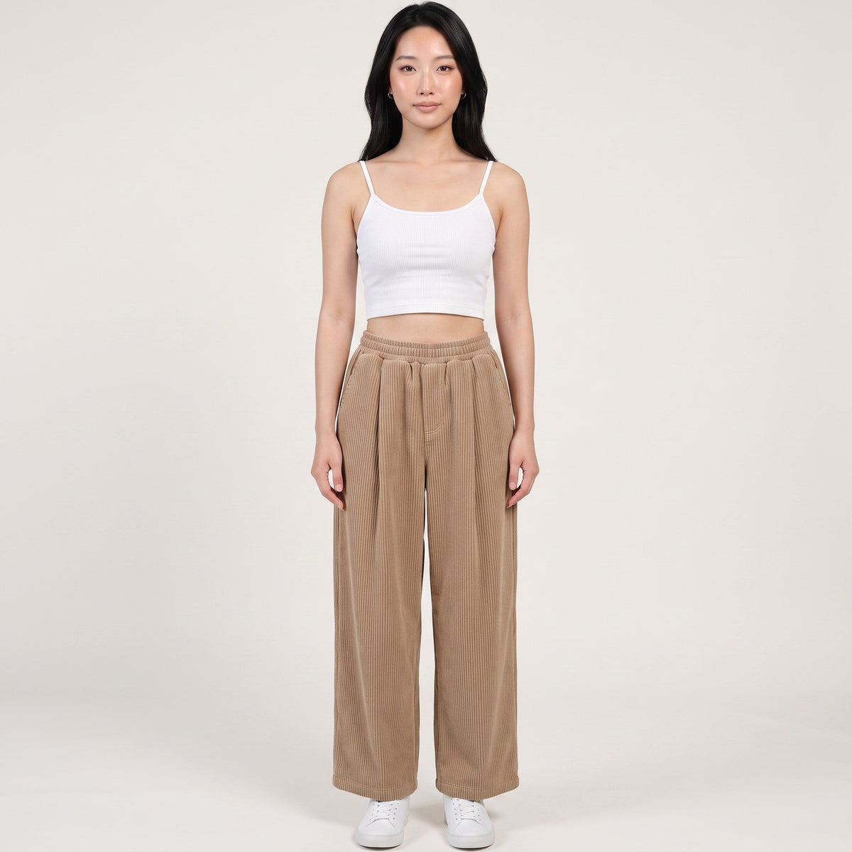 Model wearing Y2K Studio beige wide-leg corduroy trousers with an elasticated waist, paired with a white cropped top