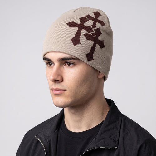 Y2K STUDIO beige acrylic knit beanie featuring a brown jacquard crucifix pattern worn by a male model