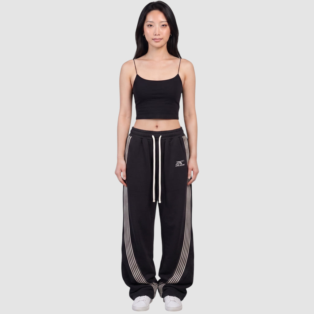 Y2K Studio black baggy fleece joggers with white side stripes and drawstring waist worn by a model