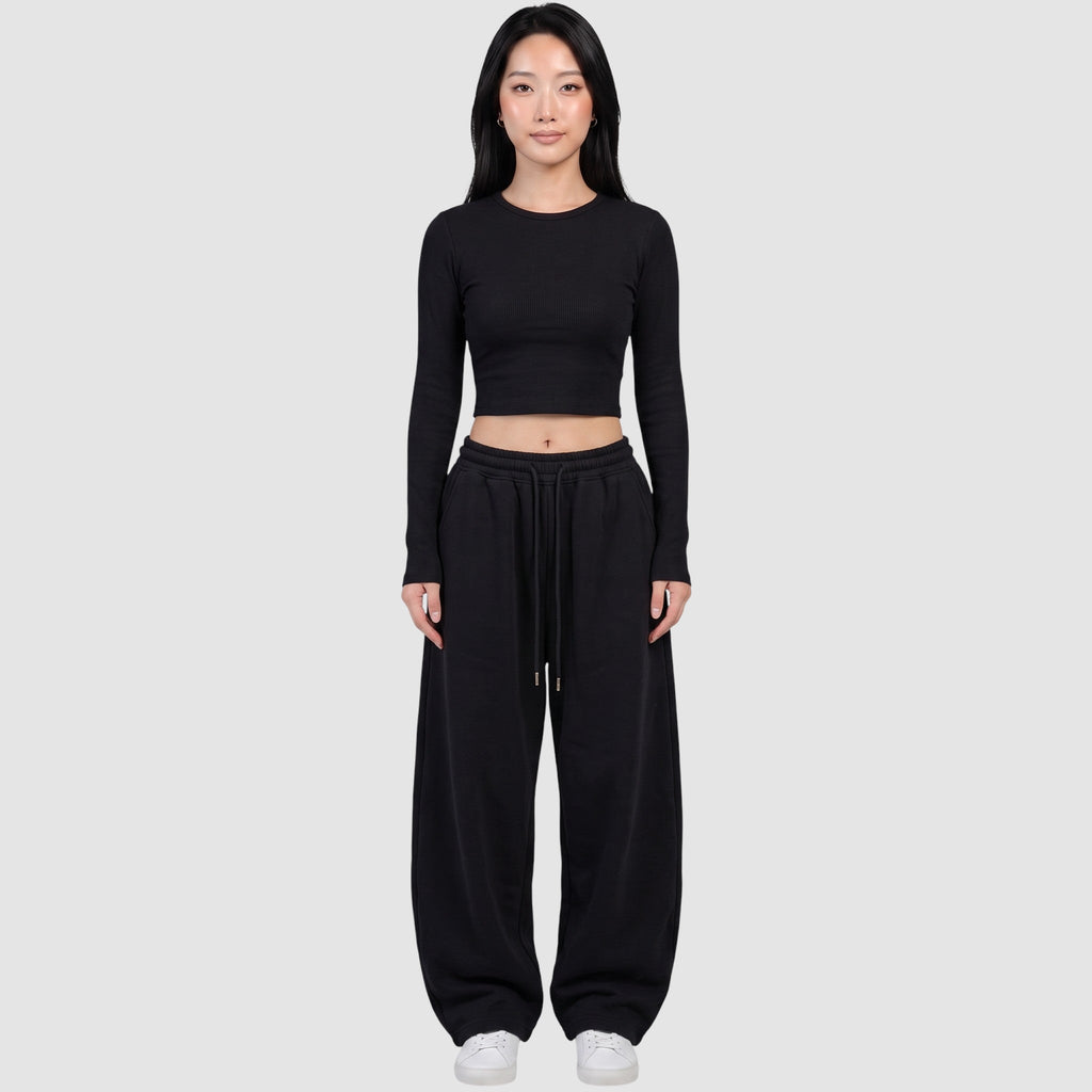 Y2K STUDIO black barrel leg sweatpants with a high elastic waist and drawstring, worn by a model with a crop top.