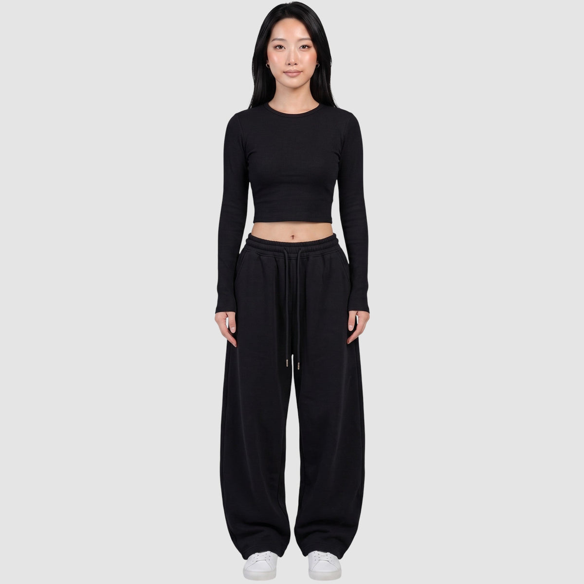 Y2K STUDIO black barrel leg sweatpants with a high elastic waist and drawstring, worn by a model with a crop top.