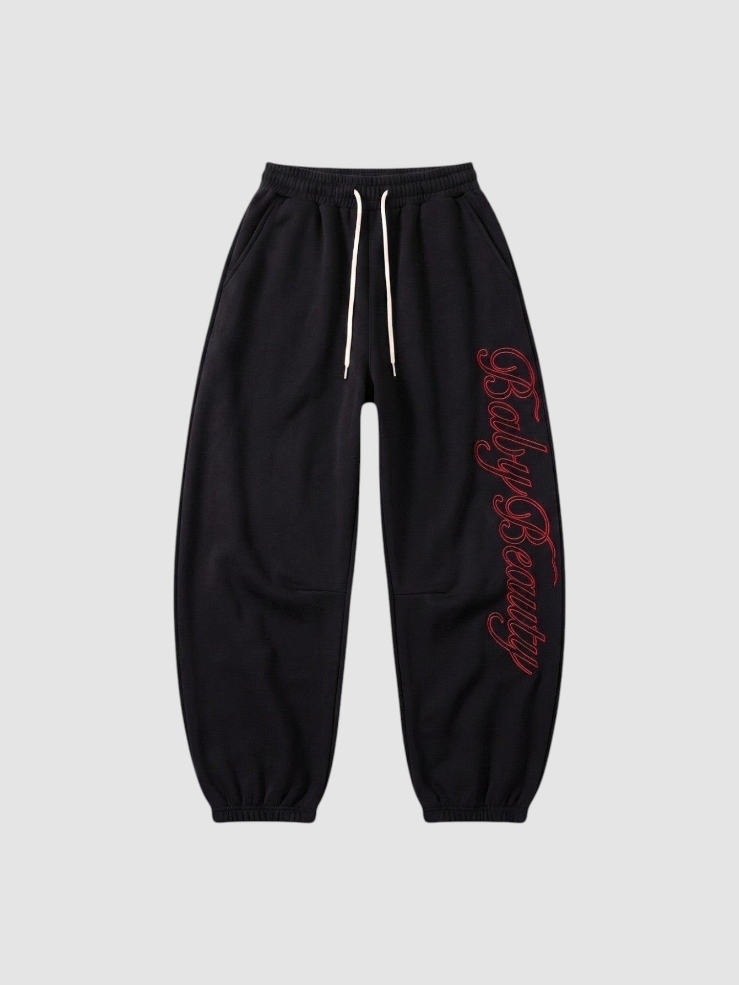 Y2K Studio black oversize joggers with red calligraphy lettering down the leg and a cream drawstring waist.