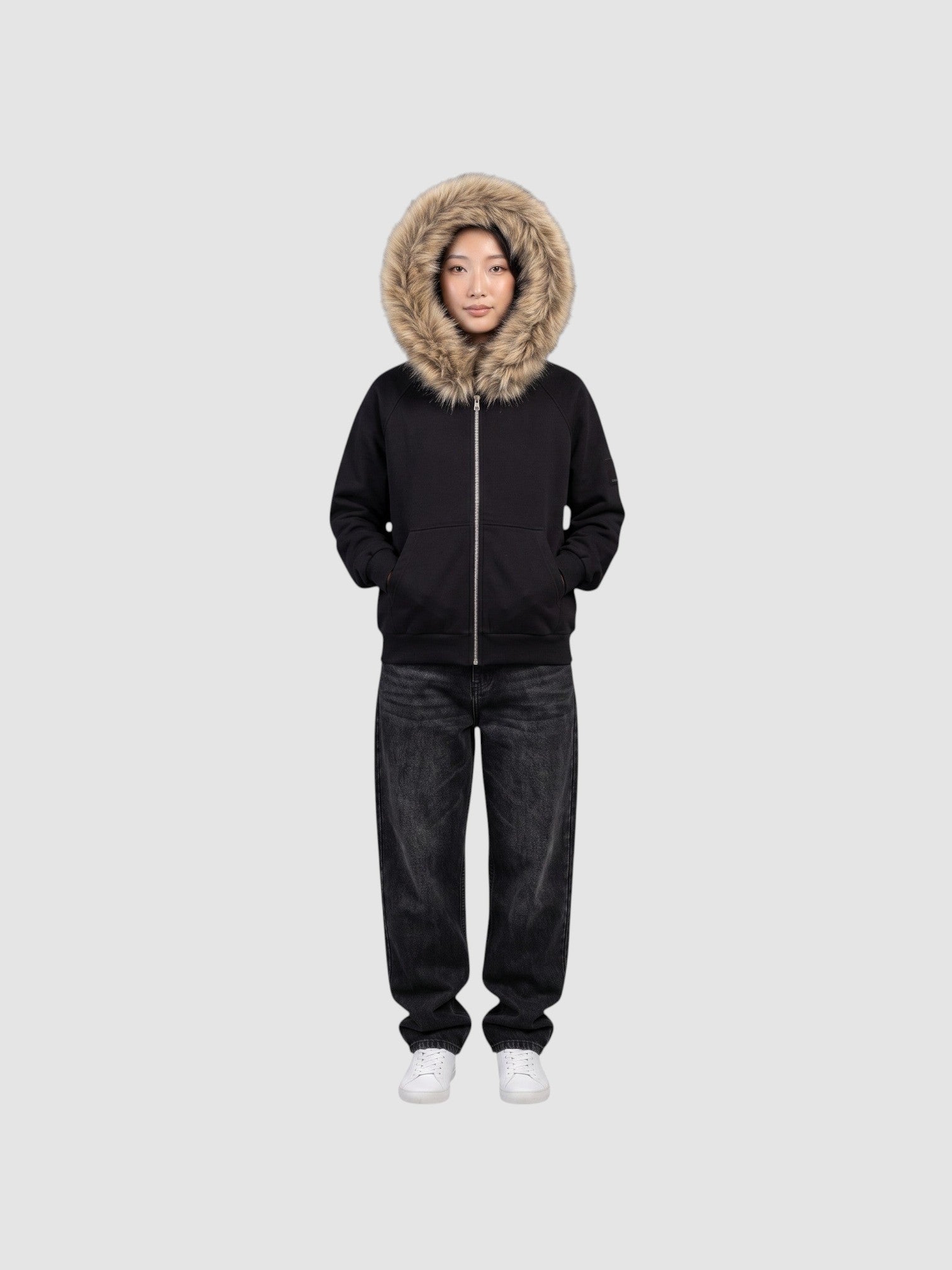 Model wearing a Y2K Studio black zip-up hoodie with a large beige faux fur hood trim and ribbed cuffs.
