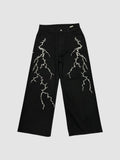 Y2K Studio black wide-leg denim jeans featuring white embroidered lightning bolt patterns on both legs.