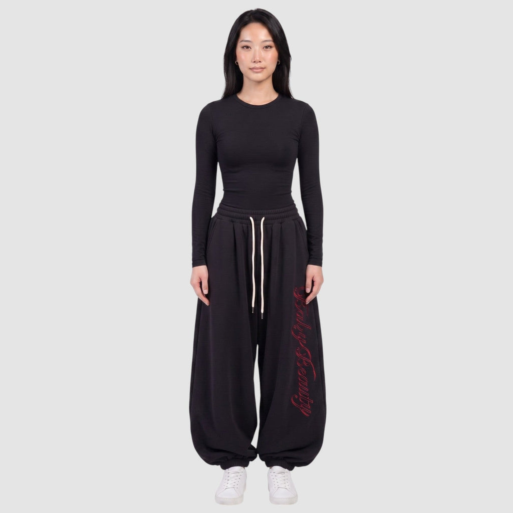 Y2K Studio black oversize joggers featuring red vertical calligraphy lettering on the leg and a cream drawstring.