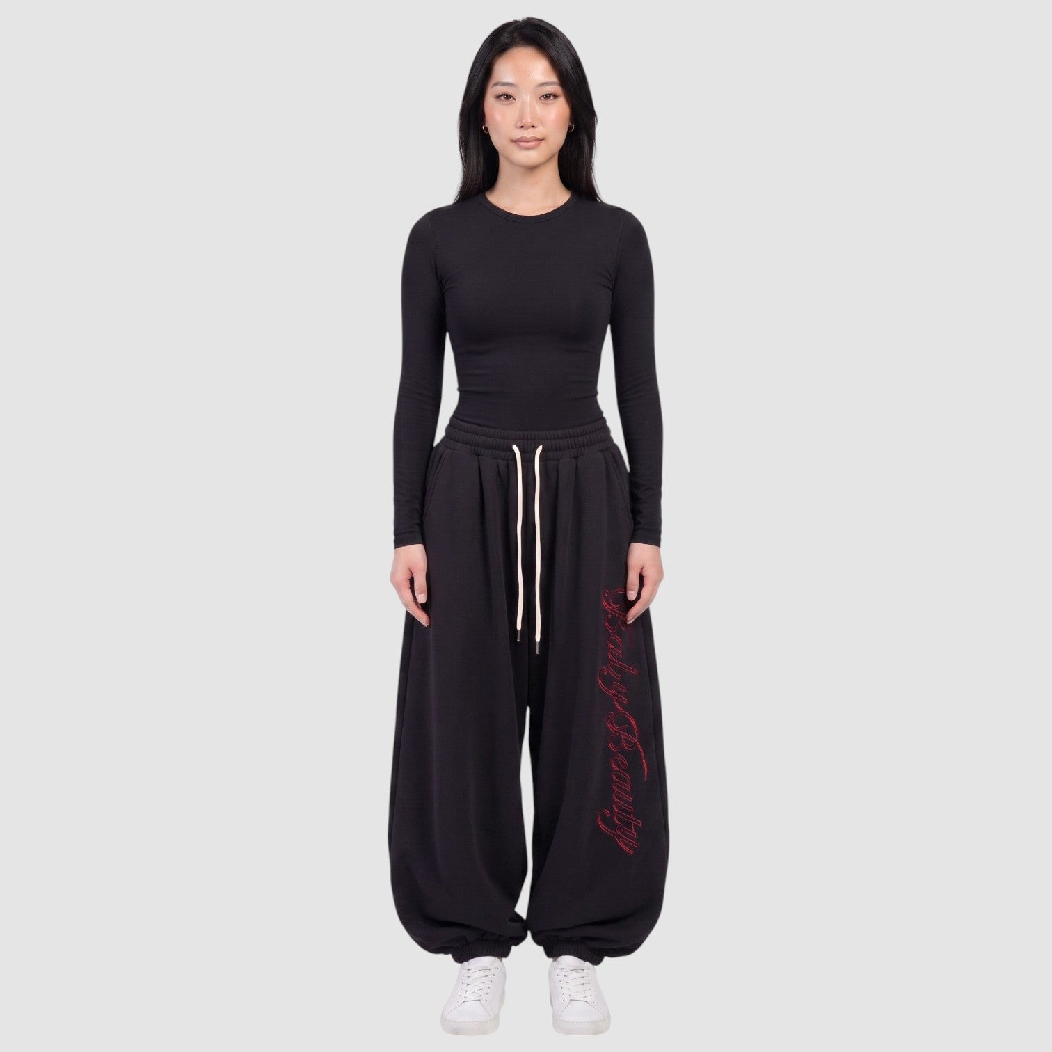 Y2K Studio black oversize joggers featuring red vertical calligraphy lettering on the leg and a cream drawstring.