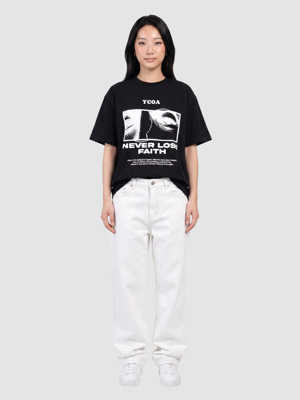 Model wearing a black Y2K Studio oversized cotton t-shirt with a graphic print of eyes and Never Lose Faith text.