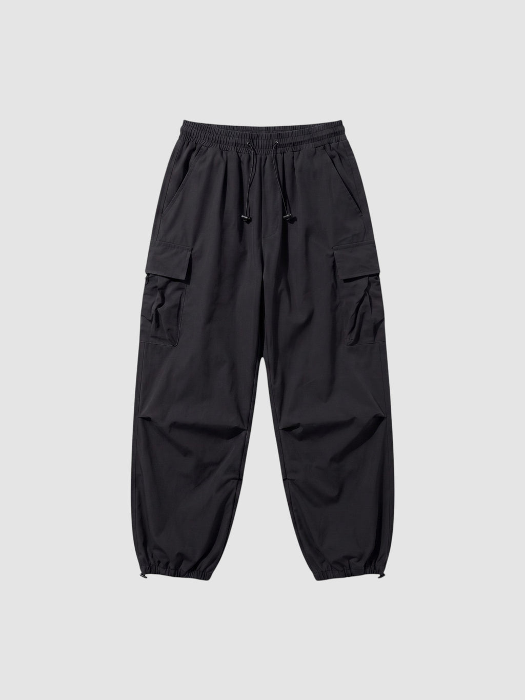 Y2K Studio black parachute cargo pants with a loose fit, elastic drawstring waist, and side flap pockets.