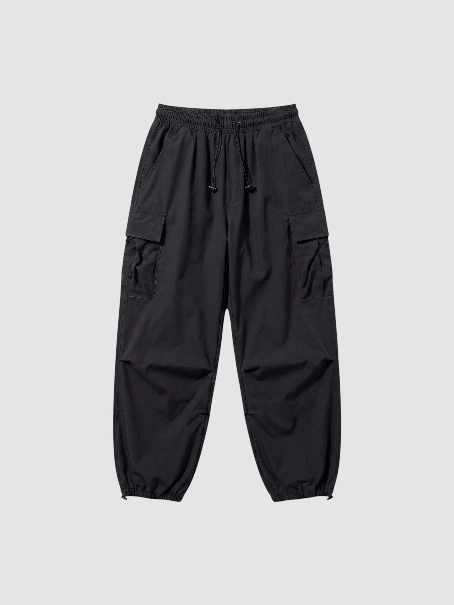 Y2K Studio black parachute cargo pants with a loose fit, elastic drawstring waist, and side flap pockets.