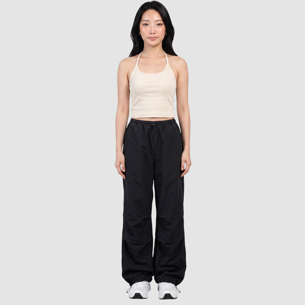 Model wearing Y2K STUDIO black parachute pants with a high elastic waist, side pockets, and adjustable ankle cords.