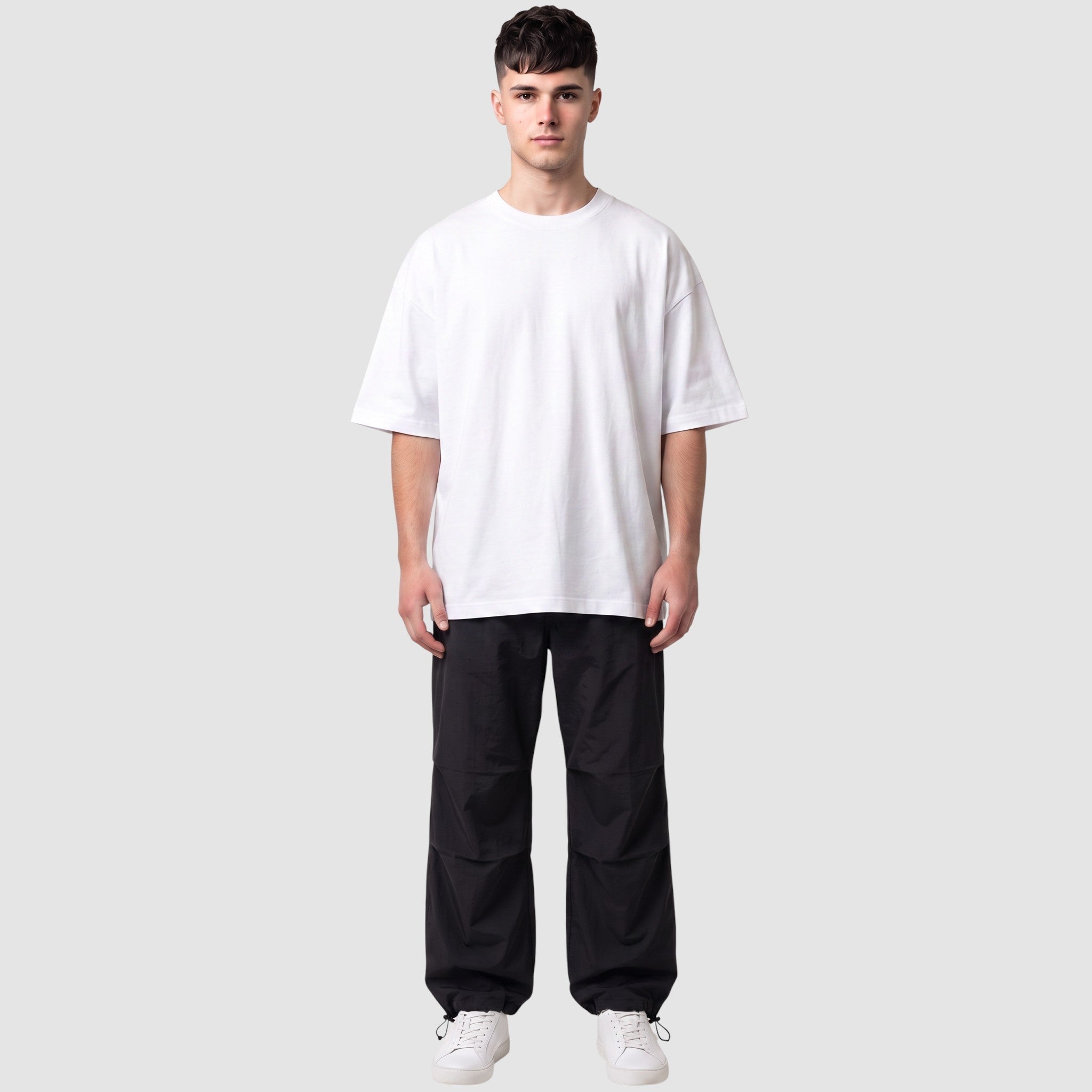Y2K STUDIO black parachute pants with elasticated waist and adjustable ankles worn by a male model in a white tee