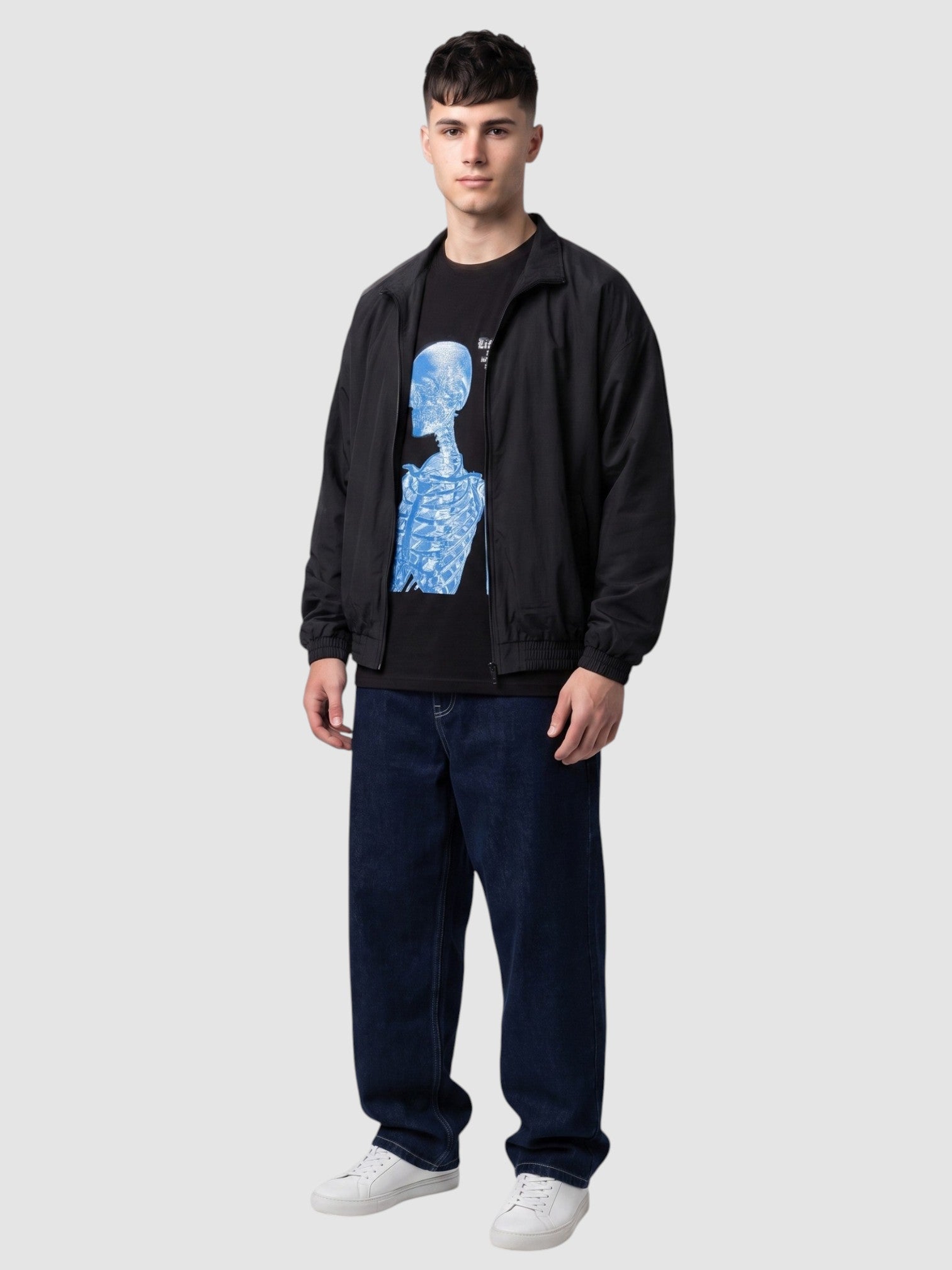 Y2K Studio black cotton t-shirt with blue skeleton graphic print worn by a man with a black jacket and baggy jeans