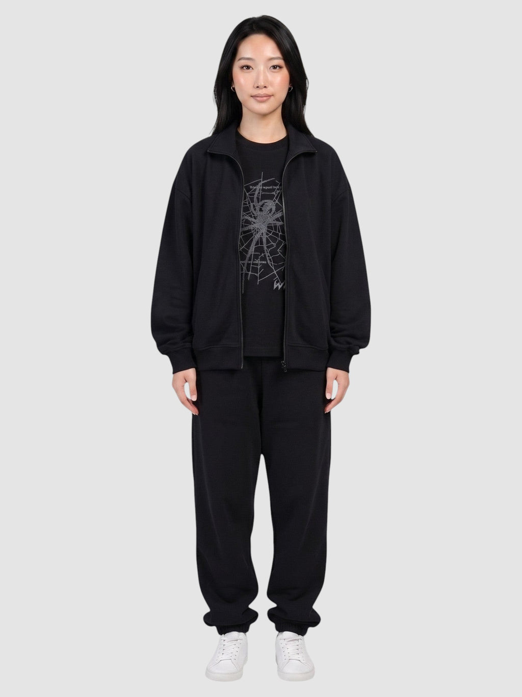 Y2K Studio black oversized t-shirt with dark grey spider web print worn by a model in a matching tracksuit