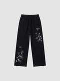 Y2K Studio black wide leg sweatpants featuring grey four-pointed star prints and an elastic drawstring waistband.