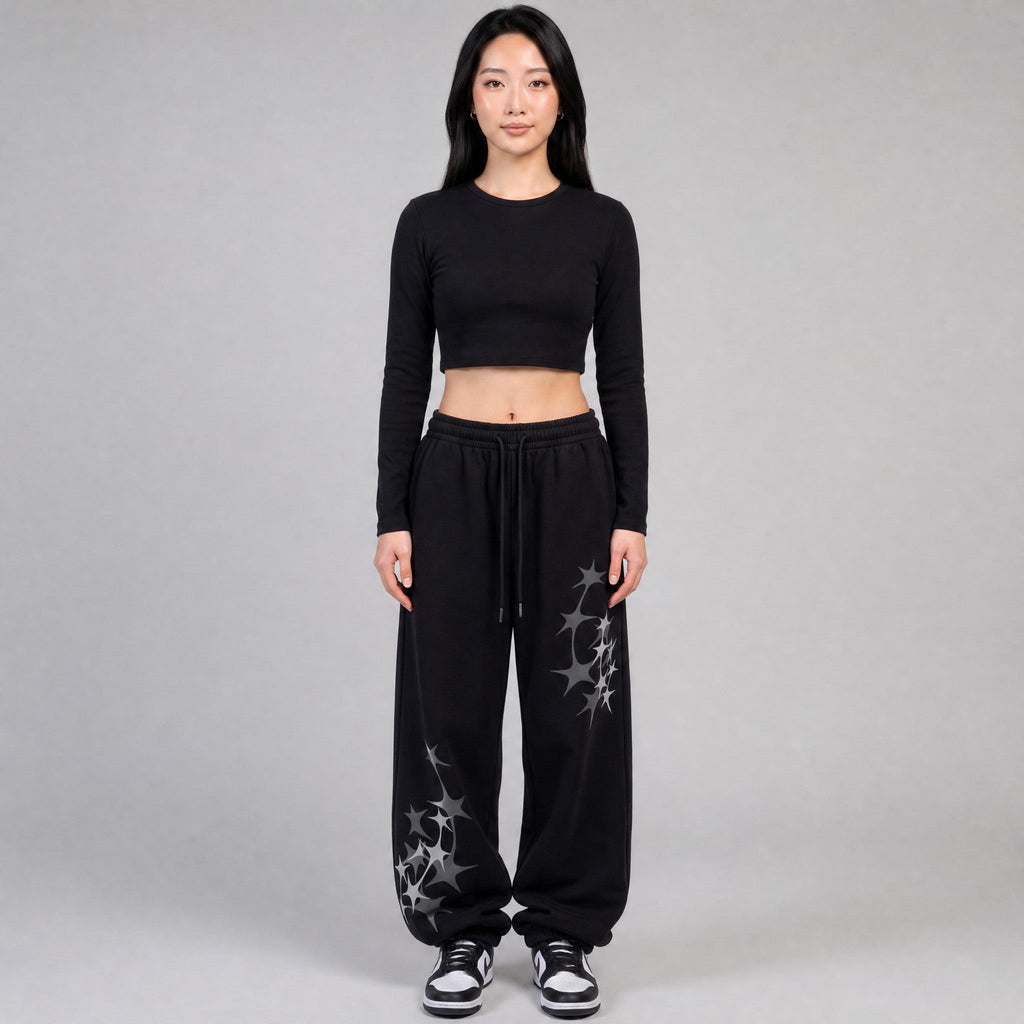 Y2K STUDIO black wide leg joggers with grey star prints, elastic waist, and white drawstring on a female model