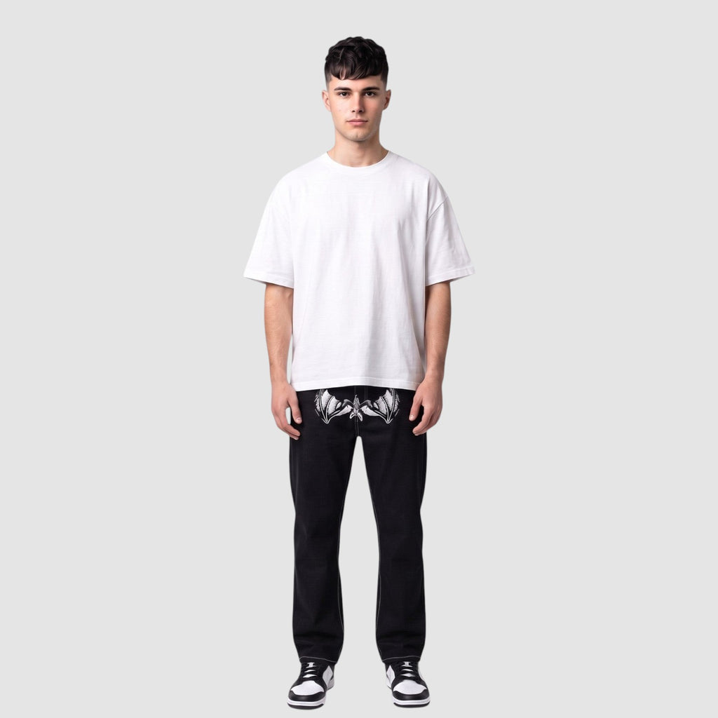 Y2K Studio black straight-leg denim jeans with white wing print on thighs and contrast stitching on a male model