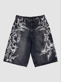 Y2K Studio black denim jorts featuring white airbrushed tribal motifs and a loose, knee-length fit with raw hems.