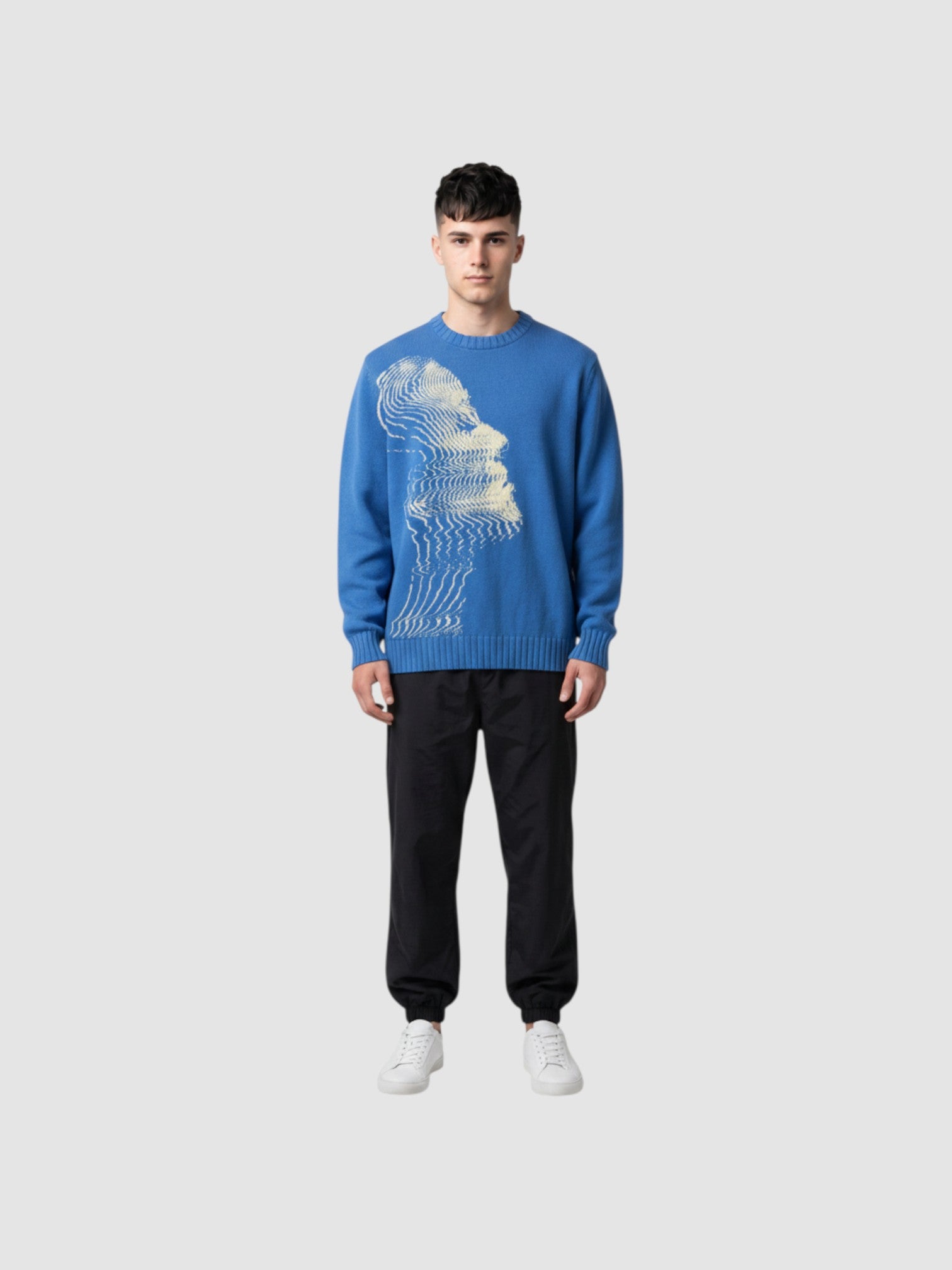 Model wearing Y2K STUDIO blue oversized knit sweater with cream wavy face graphic, paired with black cargo pants