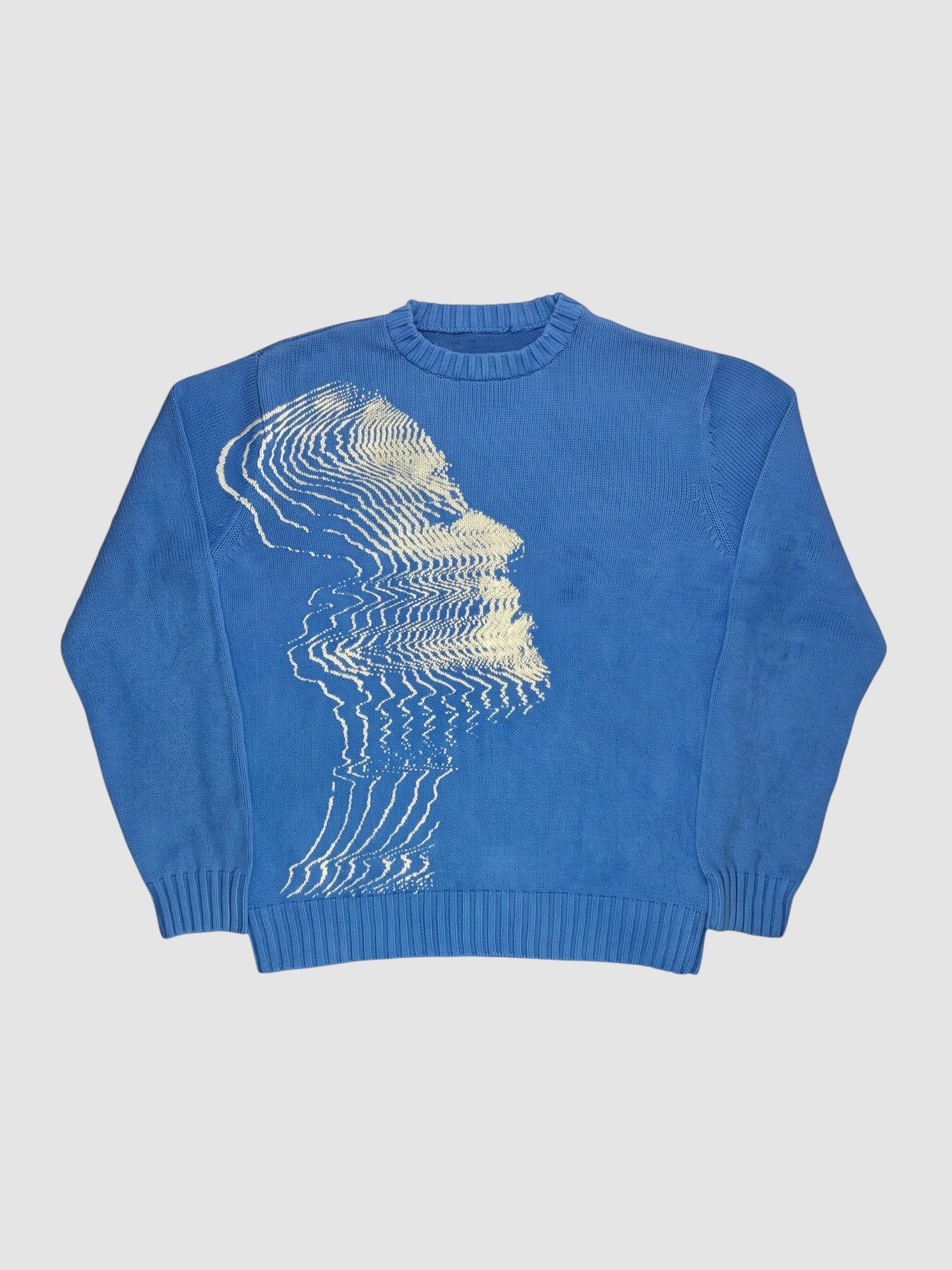 Y2K STUDIO blue oversized knit sweater featuring a cream-colored wavy face graphic in a dense polyester-acrylic blend.