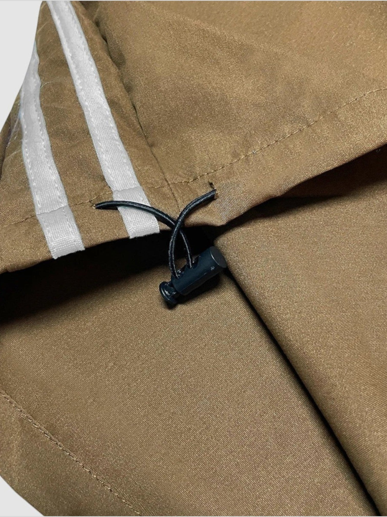 Y2K STUDIO deep brown nylon oversized joggers featuring white side stripes and an adjustable drawstring hem detail.
