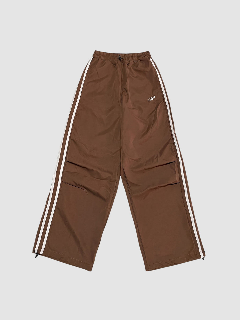 Y2K Studio brown oversized nylon joggers with white side stripes and an elastic high waist with drawstring.