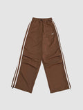 Y2K Studio brown oversized nylon joggers with white side stripes and an elastic high waist with drawstring.