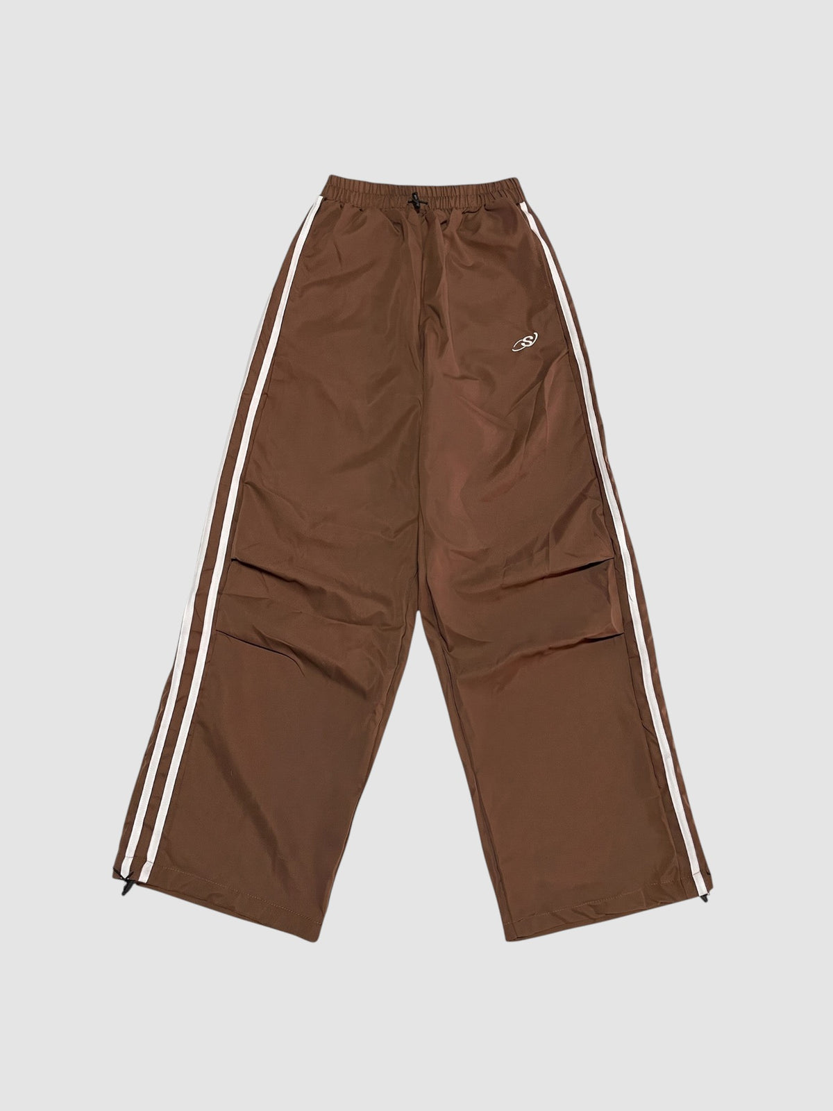 Y2K Studio brown oversized nylon joggers with white side stripes and an elastic high waist with drawstring.