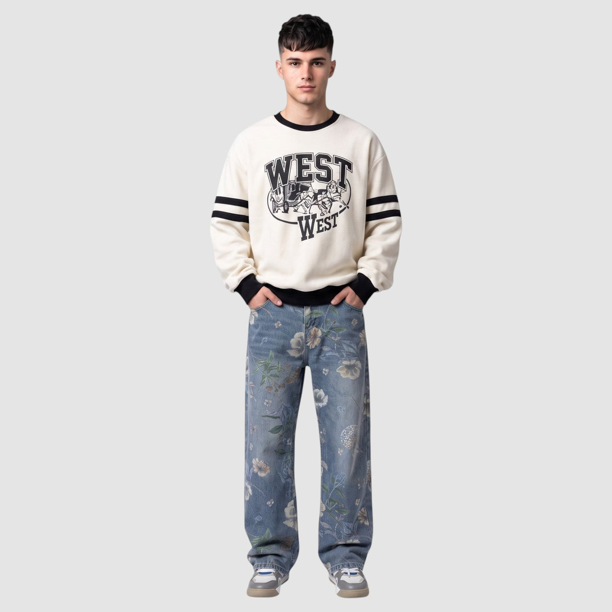 Y2K Studio light blue carpenter jeans with watercolor floral print worn by a man in a cream graphic sweatshirt.