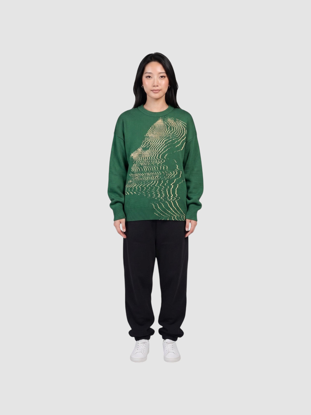 Model wearing a Y2K STUDIO forest green oversized acrylic knit sweater featuring a cream wavy face graphic pattern.