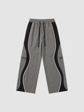 Y2K STUDIO grey and black panelled Y2K trousers with white piping, decorative zippers, and adjustable ankle cords.