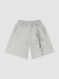 Y2K Studio grey fleece shorts with black cursive calligraphy print, elastic waist, and side pockets.