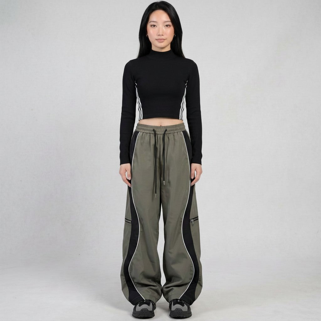 Y2K STUDIO two-tone grey panelled trousers with white piping, decorative zippers, and adjustable ankle drawstrings.