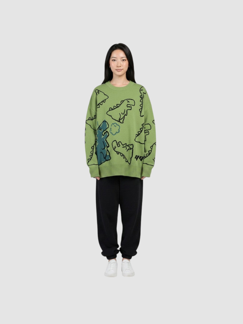 Y2K STUDIO khaki knit sweater featuring a playful cartoon dinosaur pattern, crew neck, and long sleeves on a model.