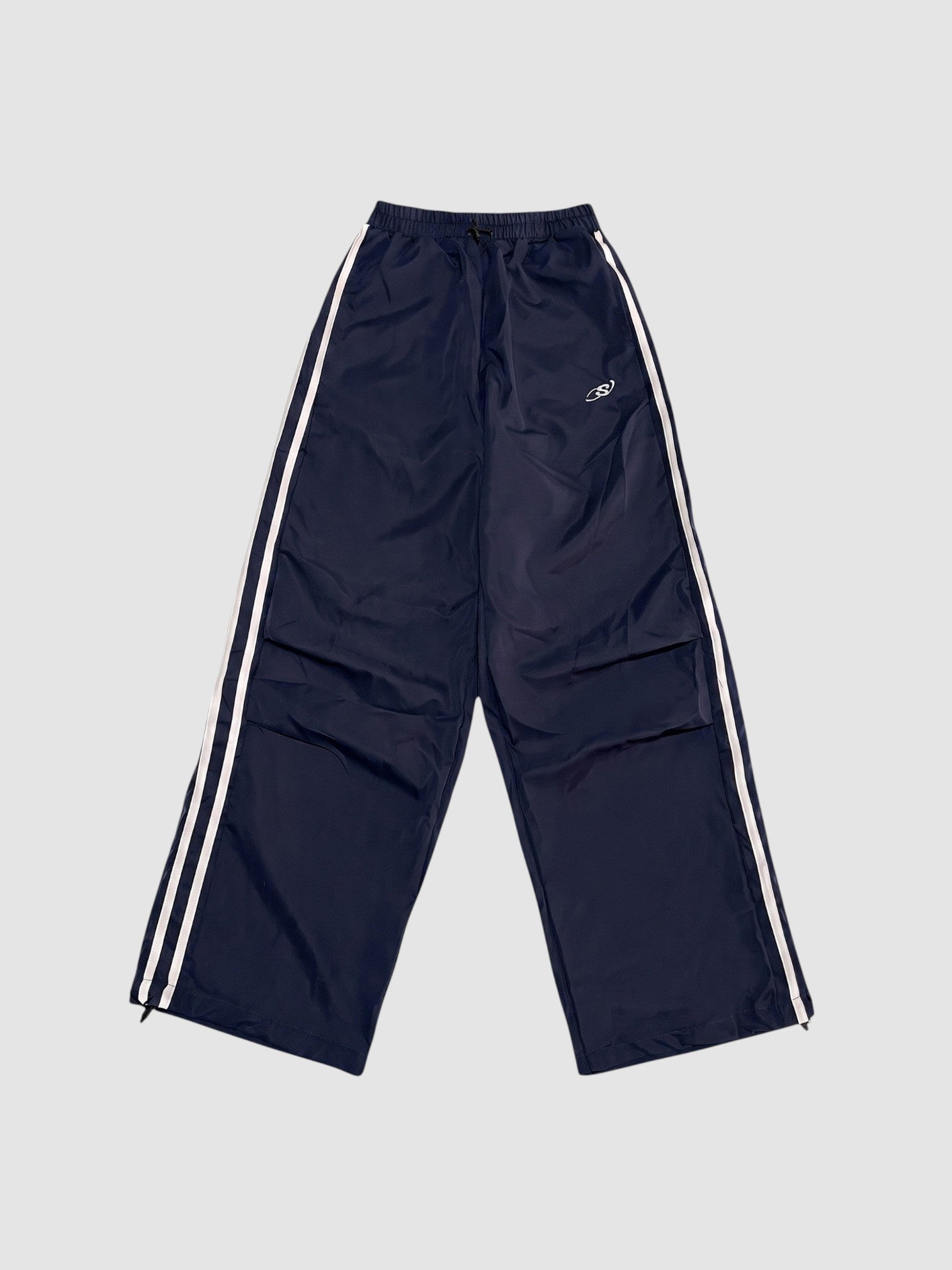 Y2K STUDIO navy blue oversized nylon joggers with white side stripes and an elastic high waist.