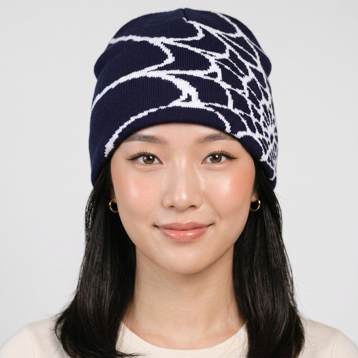 Y2K STUDIO unisex navy blue knit beanie featuring a white spider web pattern, worn by a model for winter warmth.