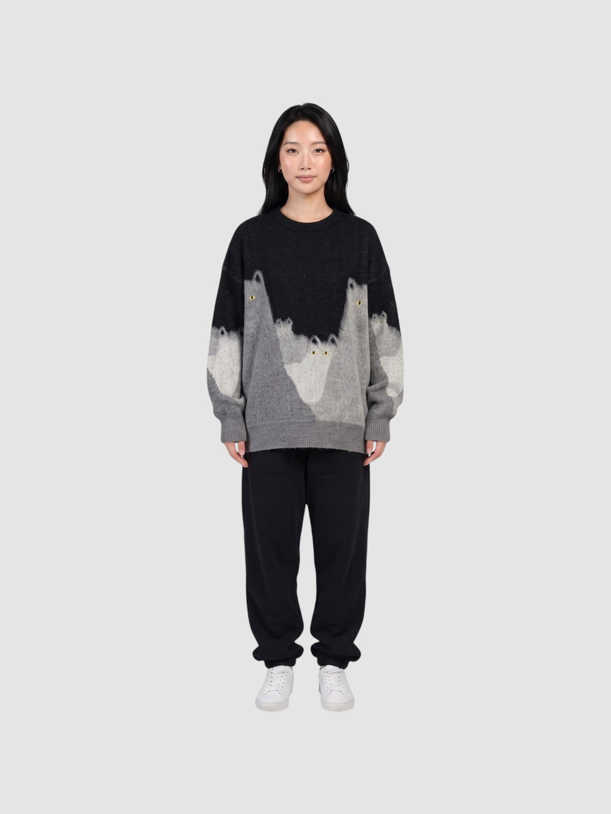Y2K STUDIO model wearing an oversized black and grey gradient knit sweater featuring cat silhouettes and yellow eyes.