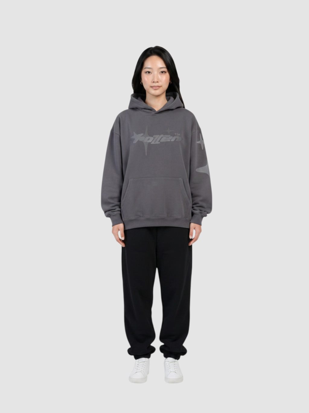 Y2K Studio oversized grey hoodie with star graphic print, worn by a model with black sweatpants and white sneakers.