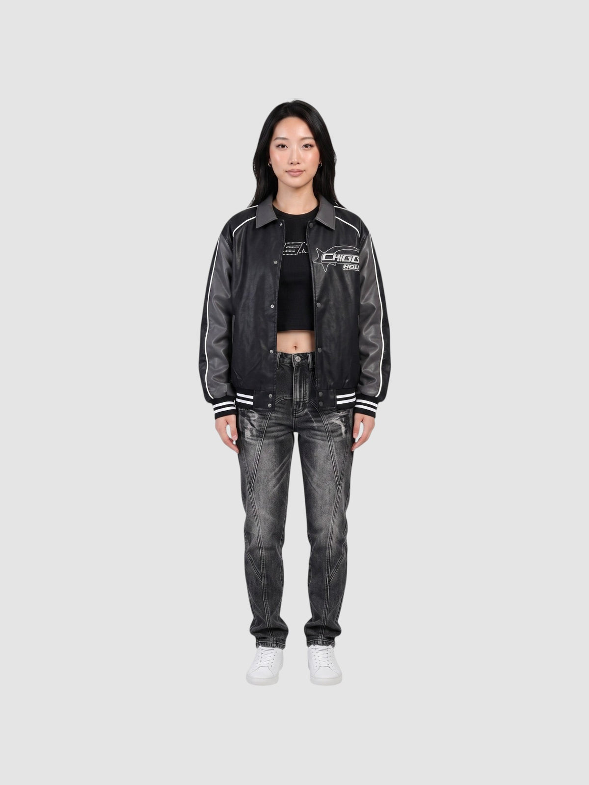 Model wearing an oversized Y2K Studio moto jacket in charcoal grey with white piping, graphic print, and ribbed cuffs.