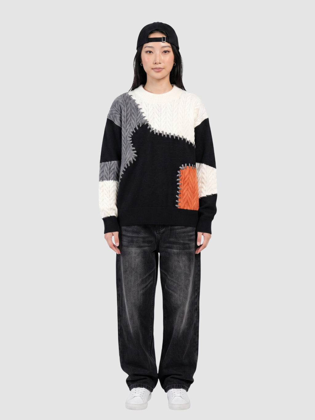 Y2K Studio patchwork knit sweater featuring black, white, and orange panels with decorative stitching on a model