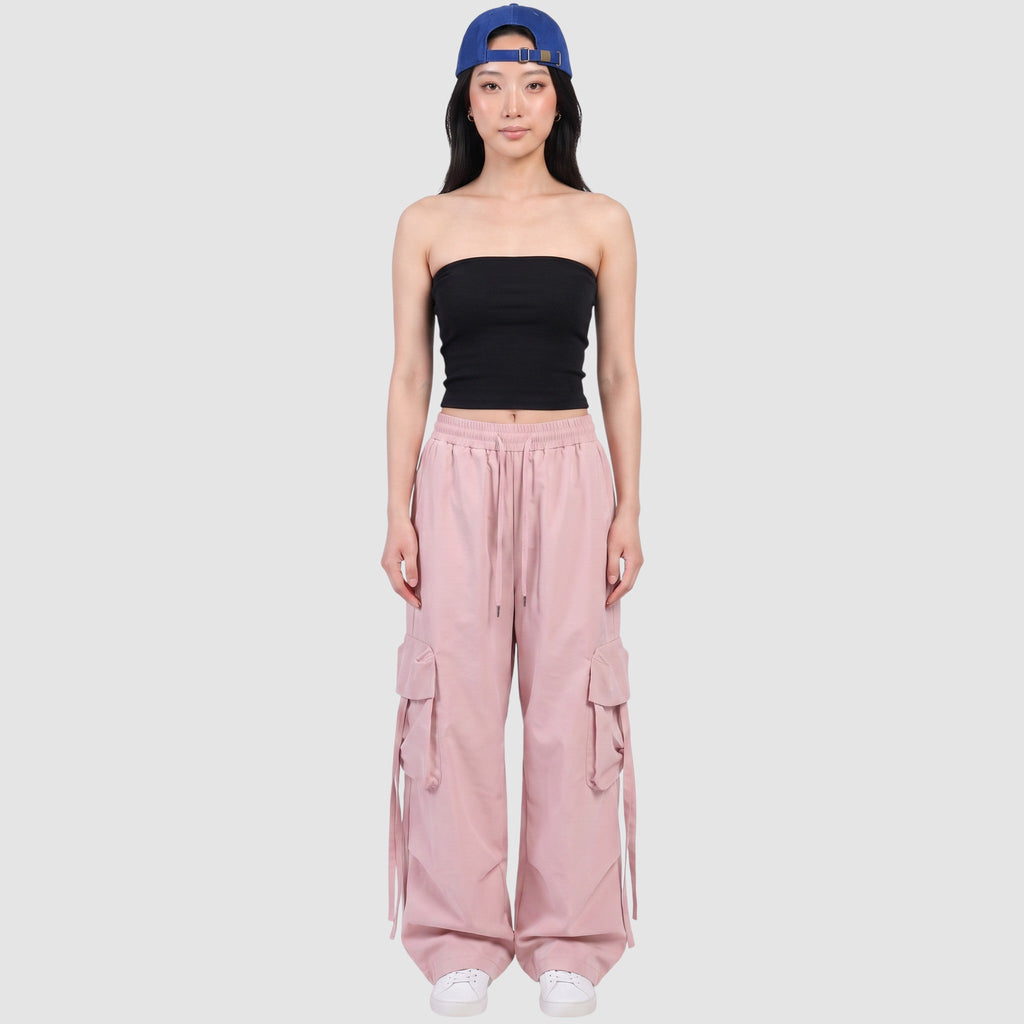 Model wearing Y2K STUDIO powder pink parachute cargo pants with side pockets, drawstring waist, and loose wide fit.