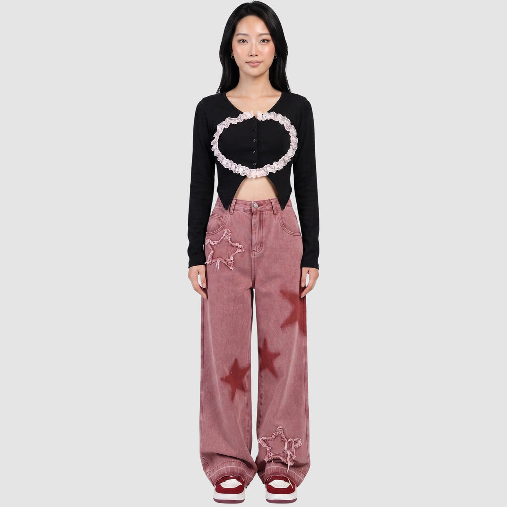 Model wearing Y2K STUDIO pink wide-leg jeans with frayed star patches and red star prints, paired with a black top.