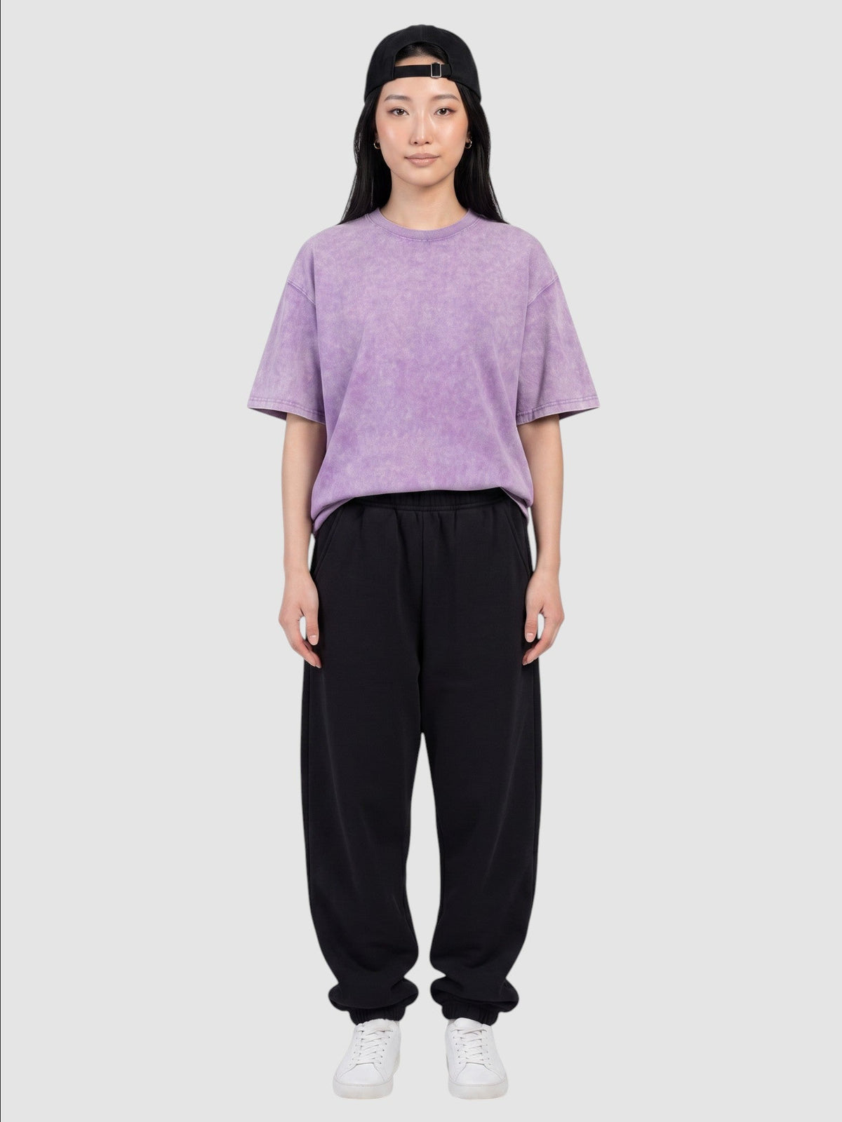 Y2K Studio purple vintage washed cotton t-shirt with a relaxed fit worn by a woman with a black cap and sweatpants
