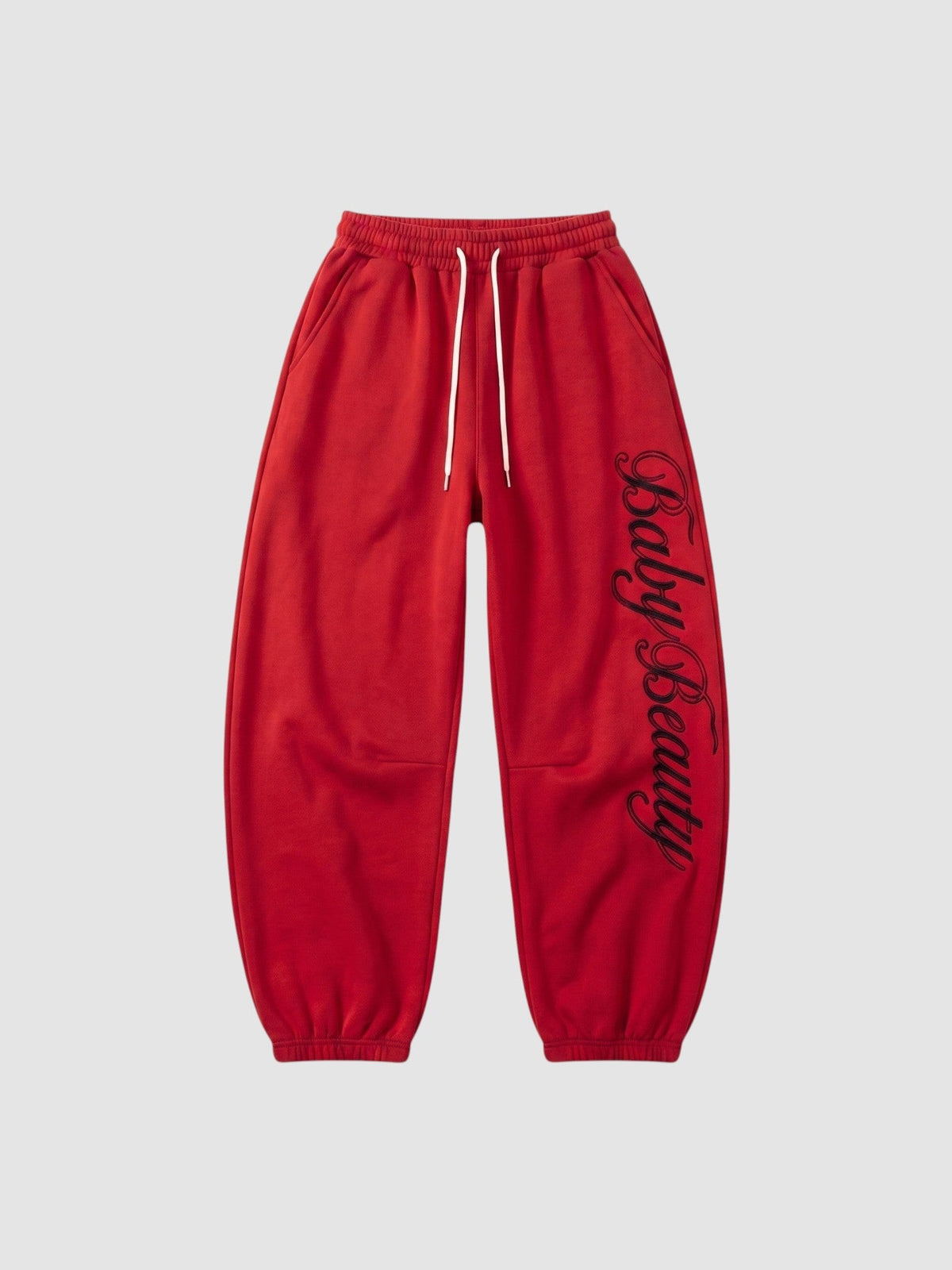 Y2K Studio red oversized joggers featuring black calligraphy lettering down the leg and a cream drawstring waist.