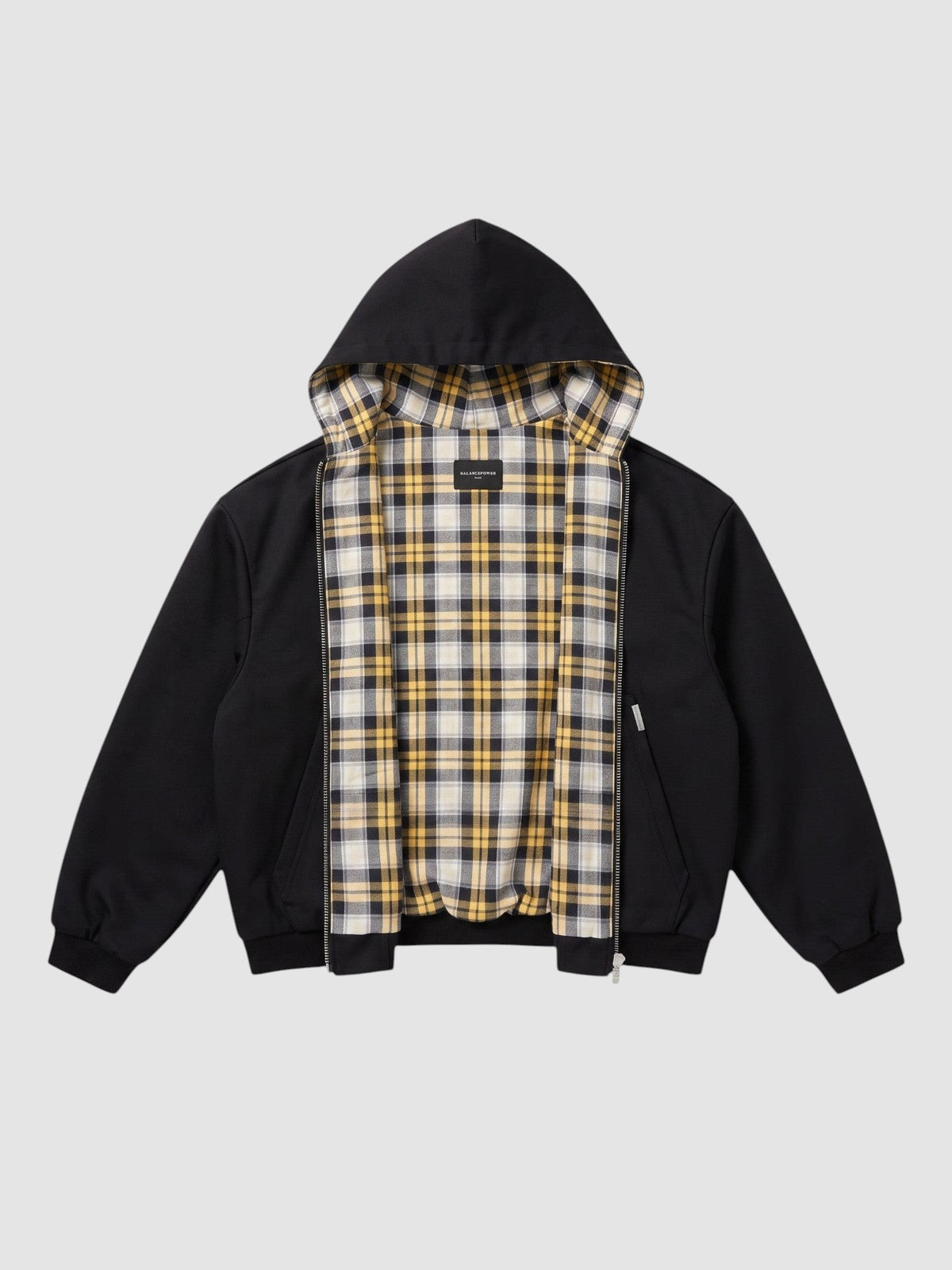 Y2K STUDIO reversible zip-up hoodie featuring a black exterior and a yellow, white, and black plaid tartan lining.