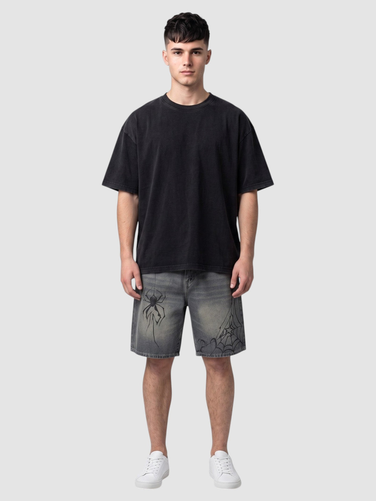 Y2K Studio model wearing Y2K spider print denim jorts in faded blue with black graphic details and a black t-shirt.
